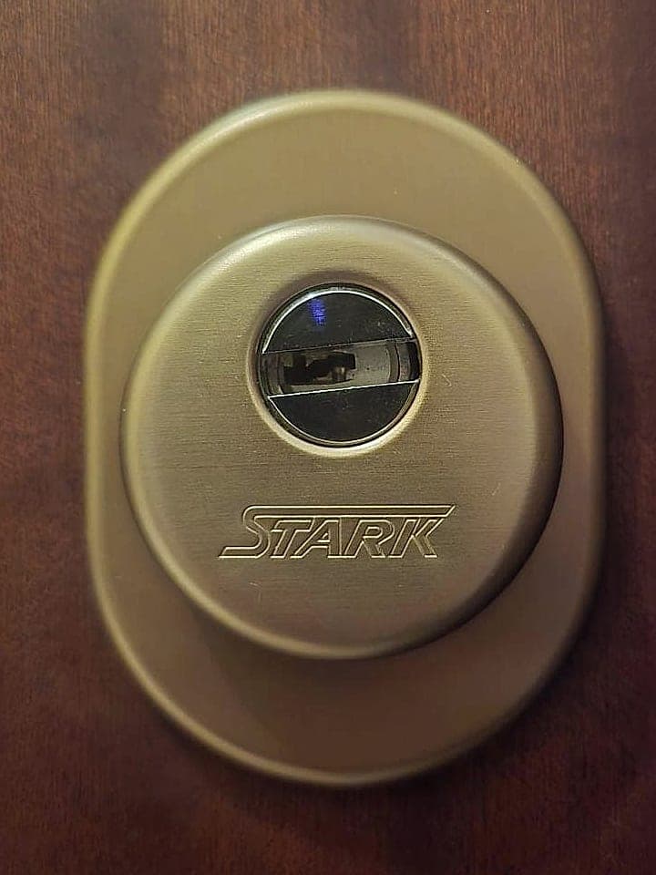 Defender di sicurezza Stark in ottone brunito su porta blindata con pannello in legno scuro