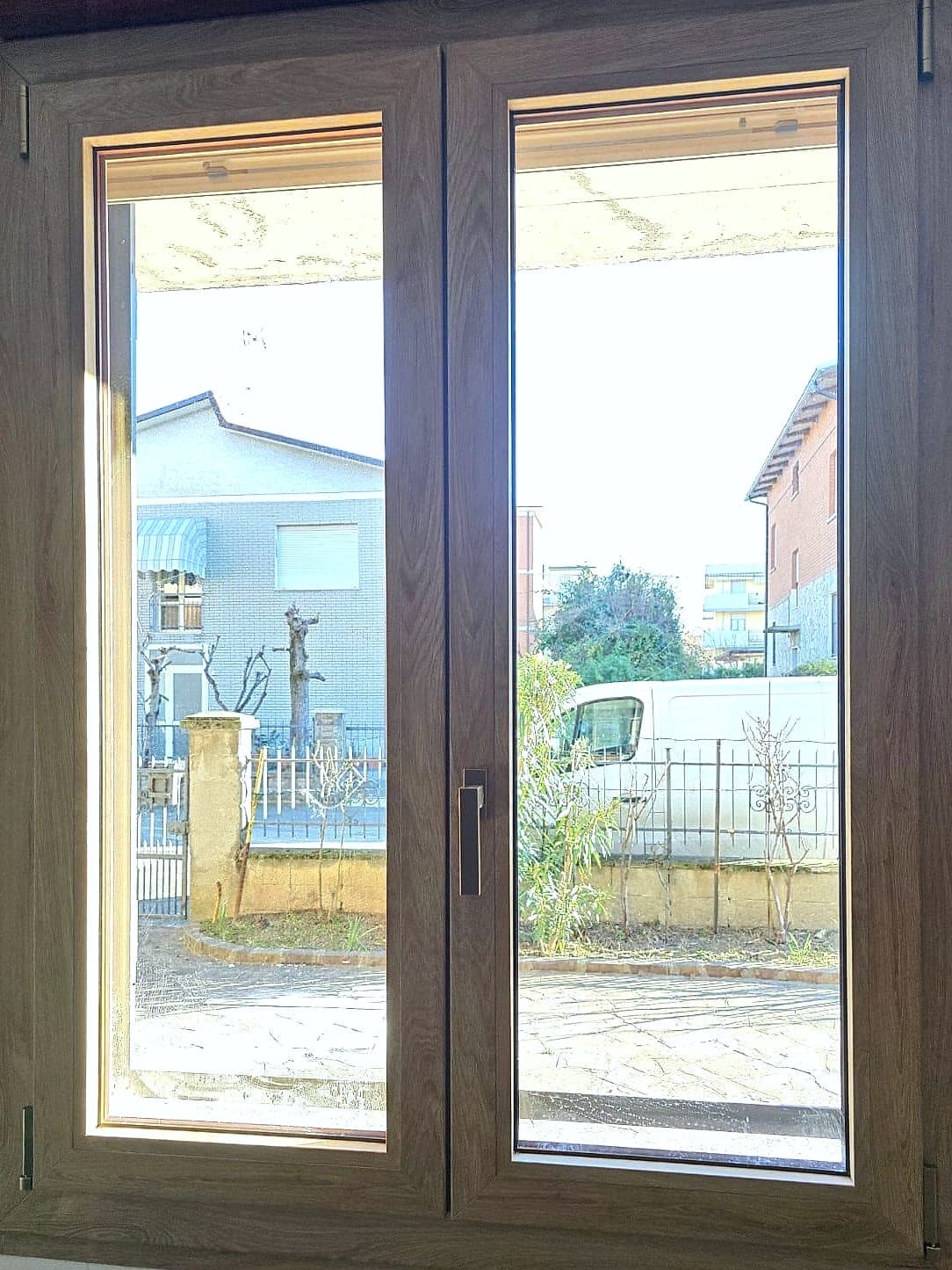 Finestra a due ante effetto legno scuro con maniglia antracite, vista dall'interno