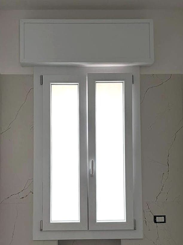 Finestra in PVC bianco a due ante con vetro satinato, in un bagno rivestito in gres effetto marmo
