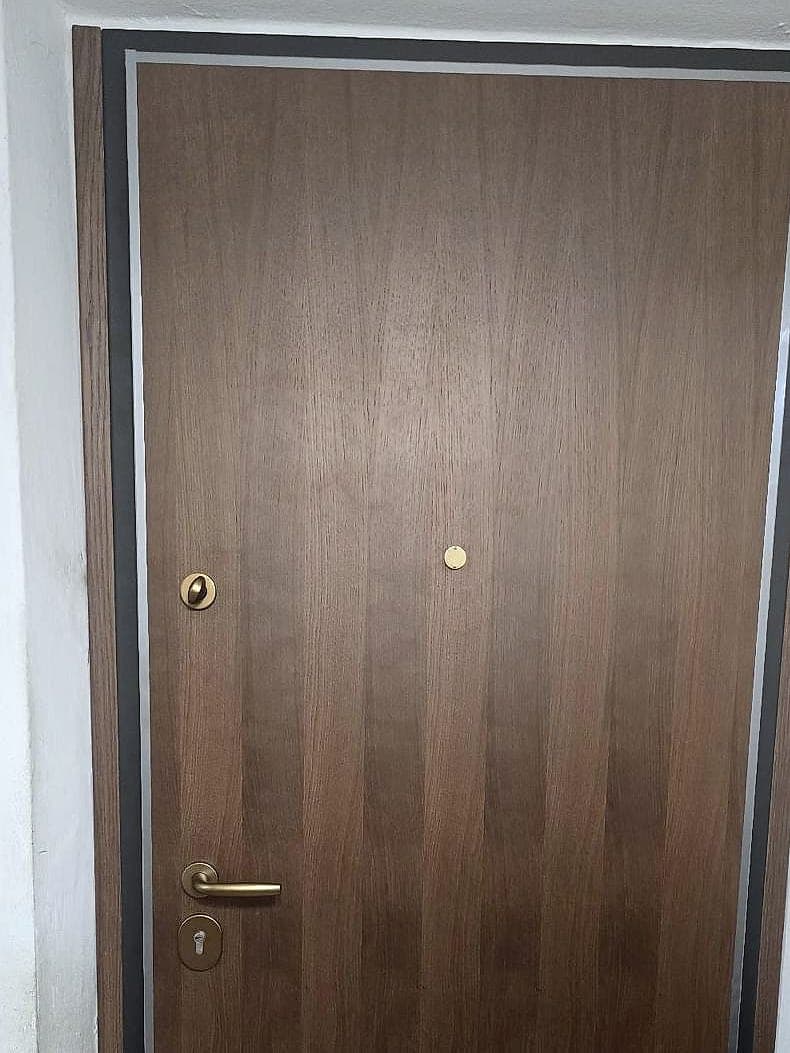 Porta blindata vista dall'ingresso, con pannello effetto noce e maniglieria in ottone