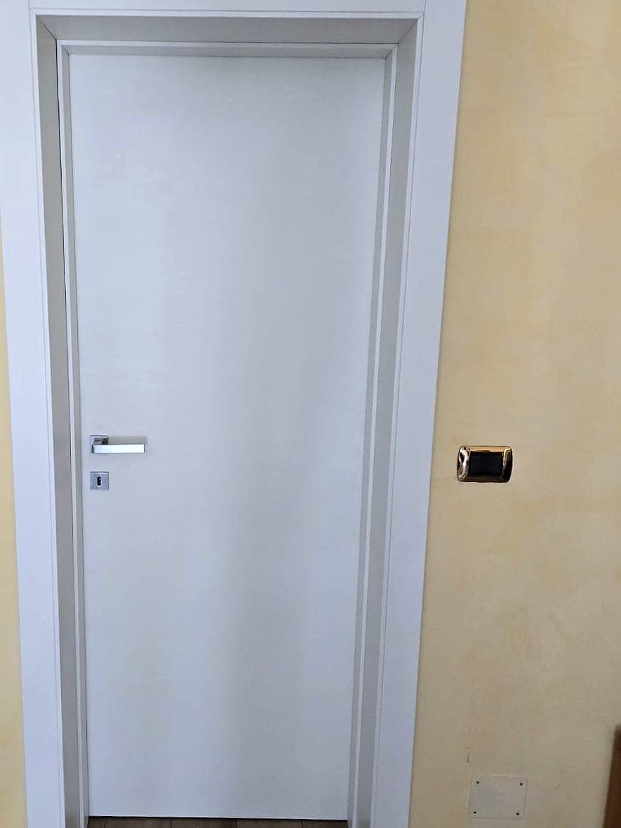 Porta interna a battente bianca con maniglia cromata satinata e coprifili squadrati