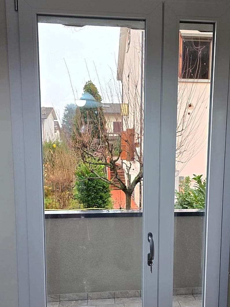 Portafinestra bianca a due ante affacciata sul balcone, vista dall'interno della cucina