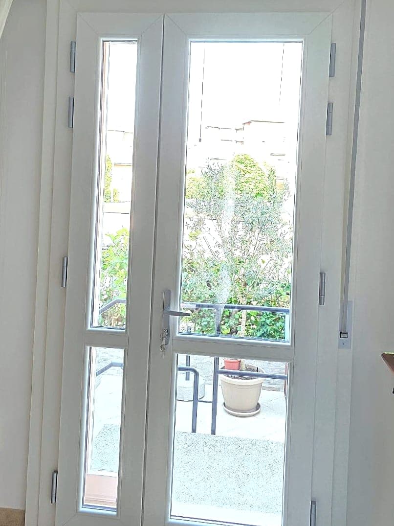 Portafinestra bianca a due ante con scuri interni ripiegati e cassonetto per tapparella