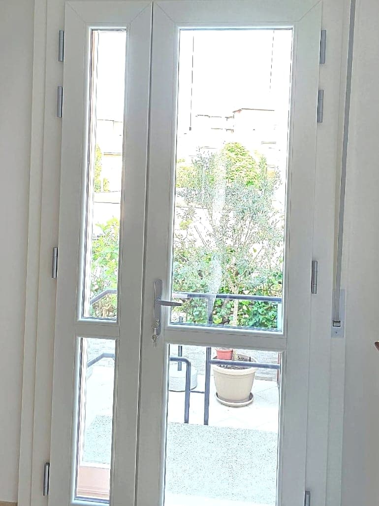 Portafinestra bianca a due ante con cassonetto coprirullo, vista dall'interno del soggiorno