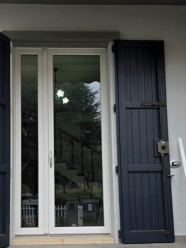 Portoncino d'ingresso bianco a vetri con scuri in legno antracite, esterno di una villetta